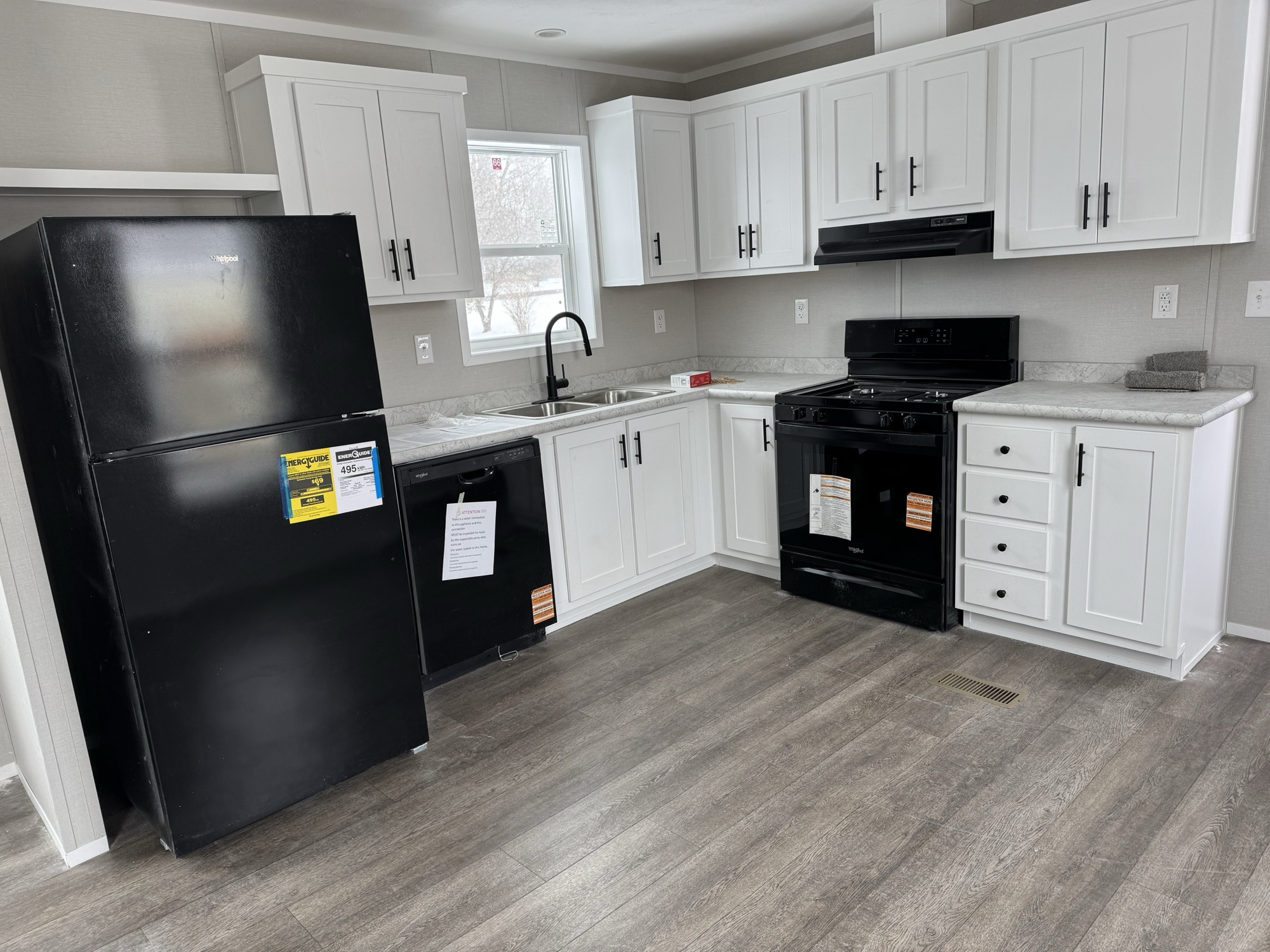 New manufactured home kitchen — Limestone community, Finger Lakes NY. White shaker cabinets, black appliances, and laminate countertops.